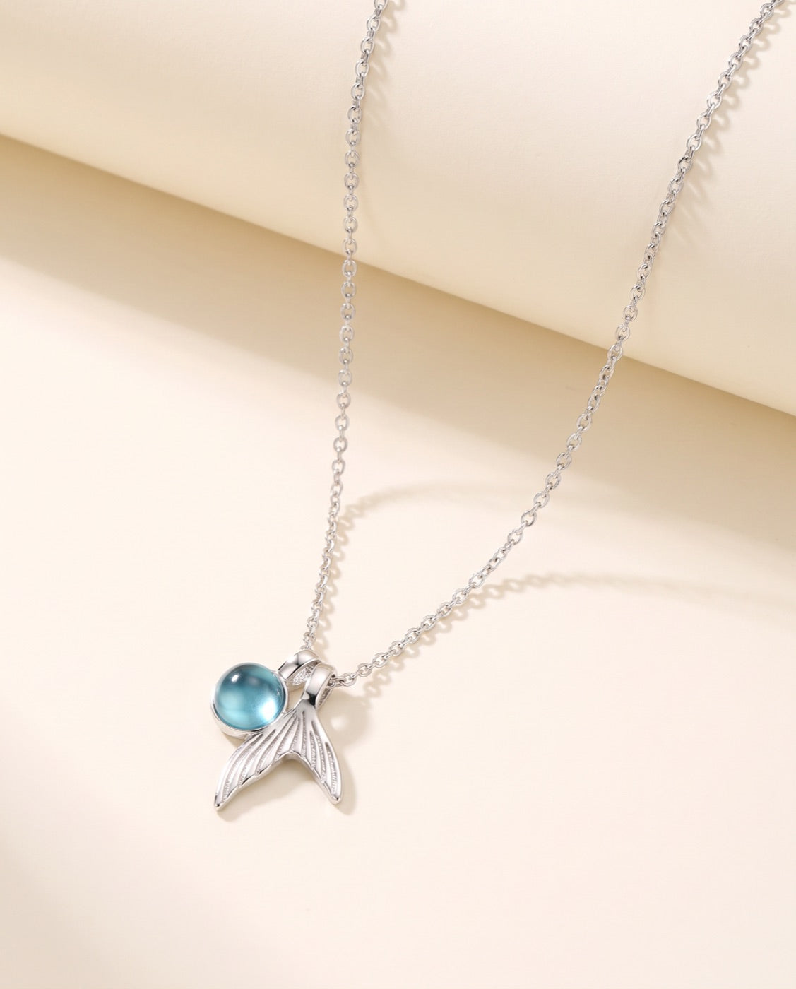 Kette Marina, Meerjungfrauenschwanz aus 925 Sterlingsilber mit blauem Stein, auf Ivory